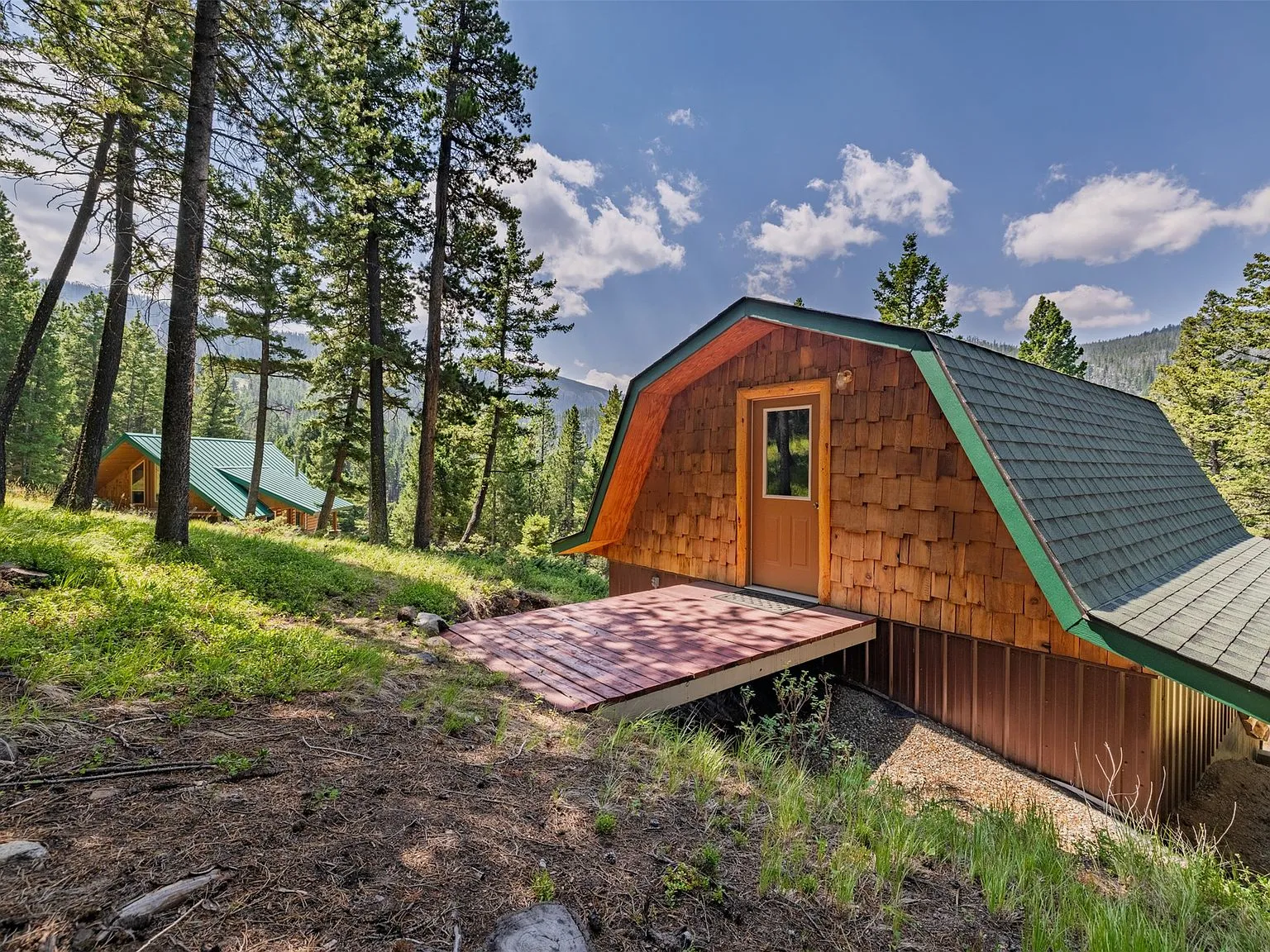 A detached A-frame outbuilding's gambrel roof and shingled gable end