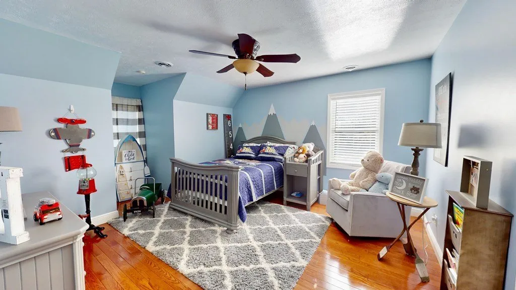 A child's bedroom with a rug, chair and blue walls