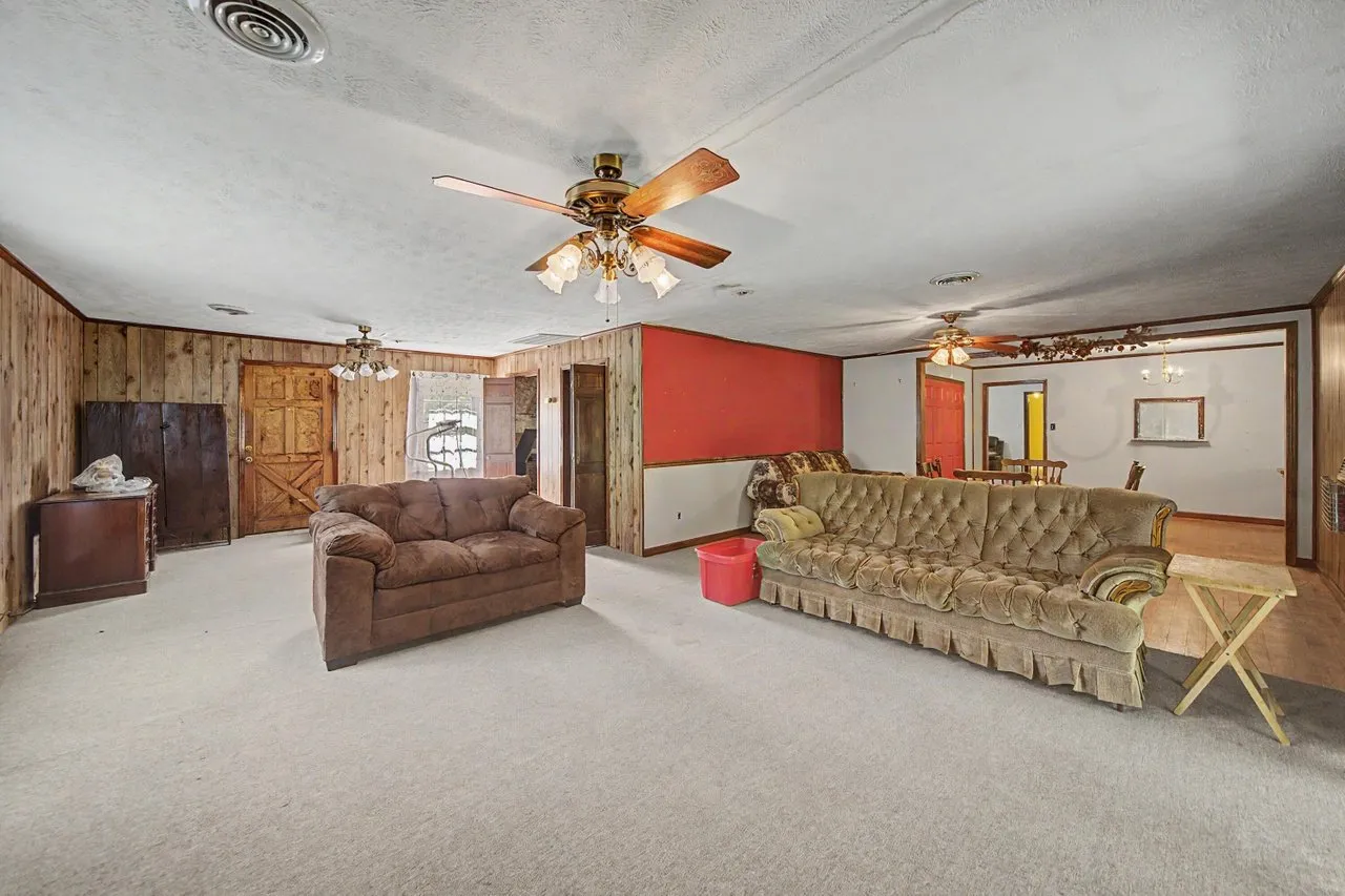 A large room with a sofa, seating and a red accent wall