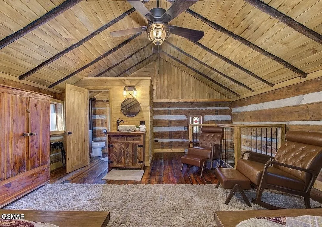 A bedroom with a fireplace and a seating area under a peaked ceiling
