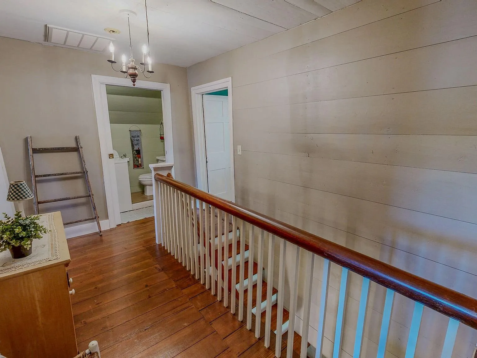 The upstairs hallway with wood flooring and a stair railing