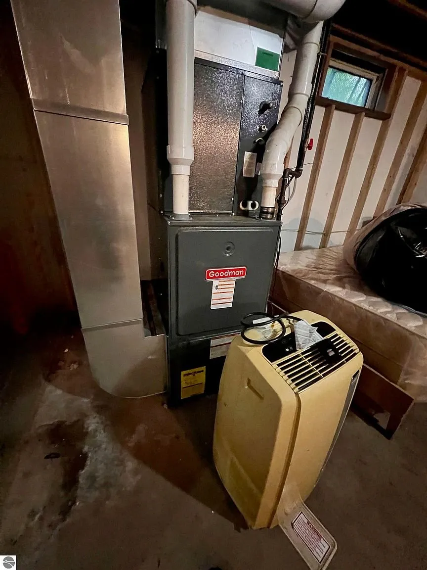 The propane furnace in the basement with the portable air conditioner beside it