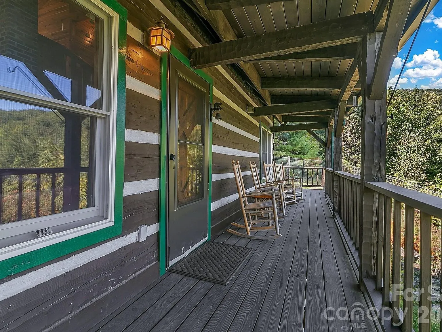 A covered porch with rocking chairs and a green-trimmed window