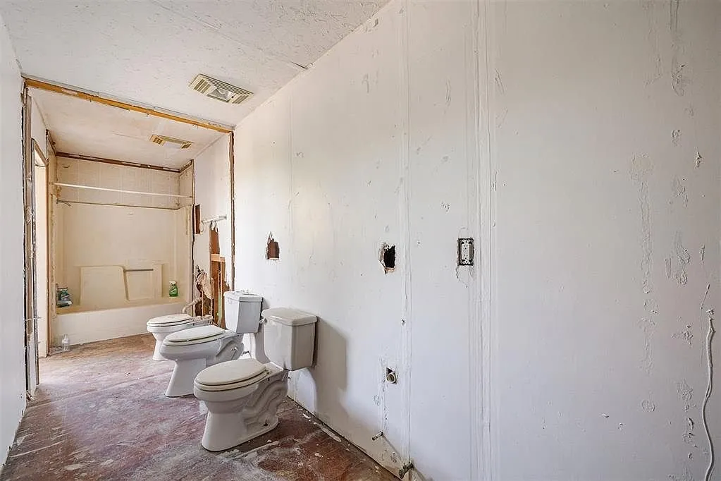 The restroom with two toilets on the floor and the stall opening