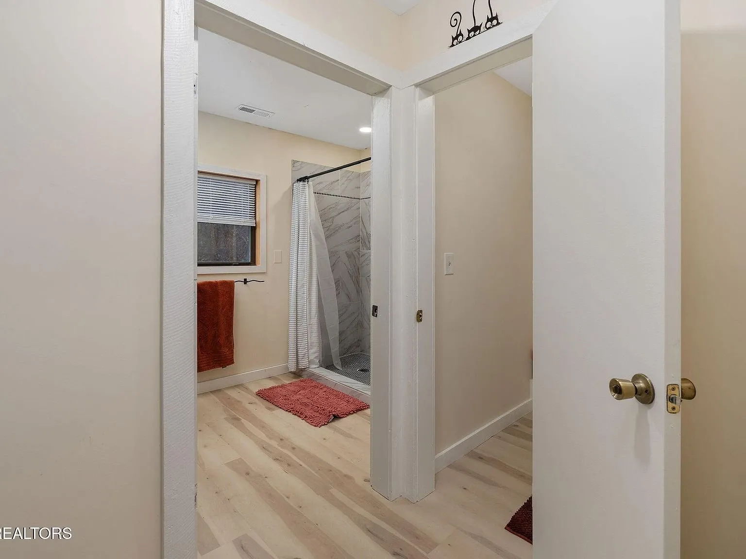 A bedroom with a bed, dresser and curtained window
