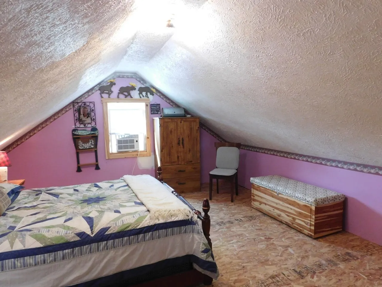 The loft with a bed under the sloped ceiling and pink walls