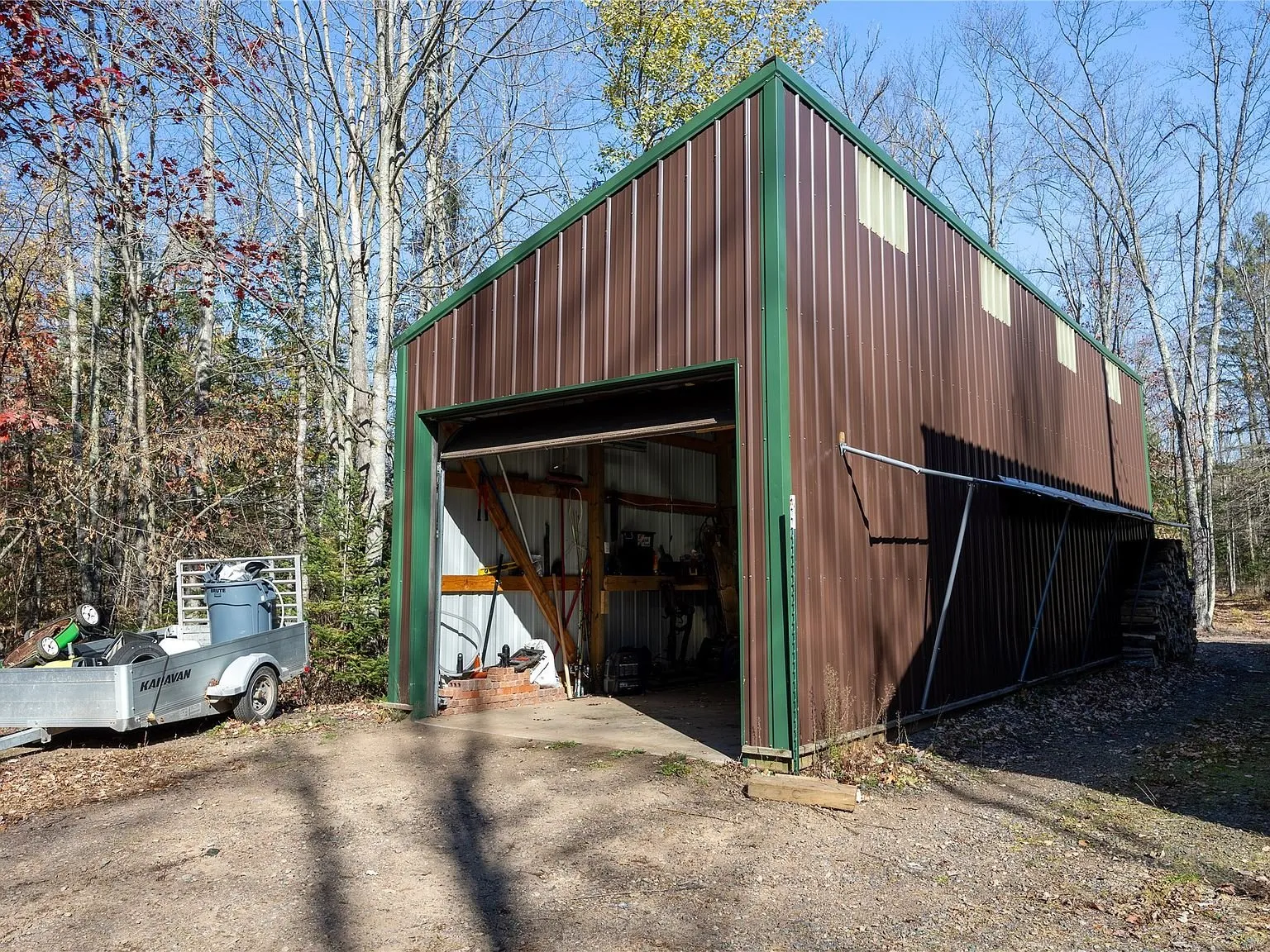 A separate metal-sided pole barn with its door open near the driveway
