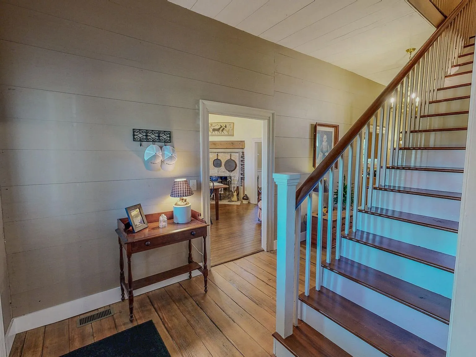 The front entry hall with a console table, lamp and staircase