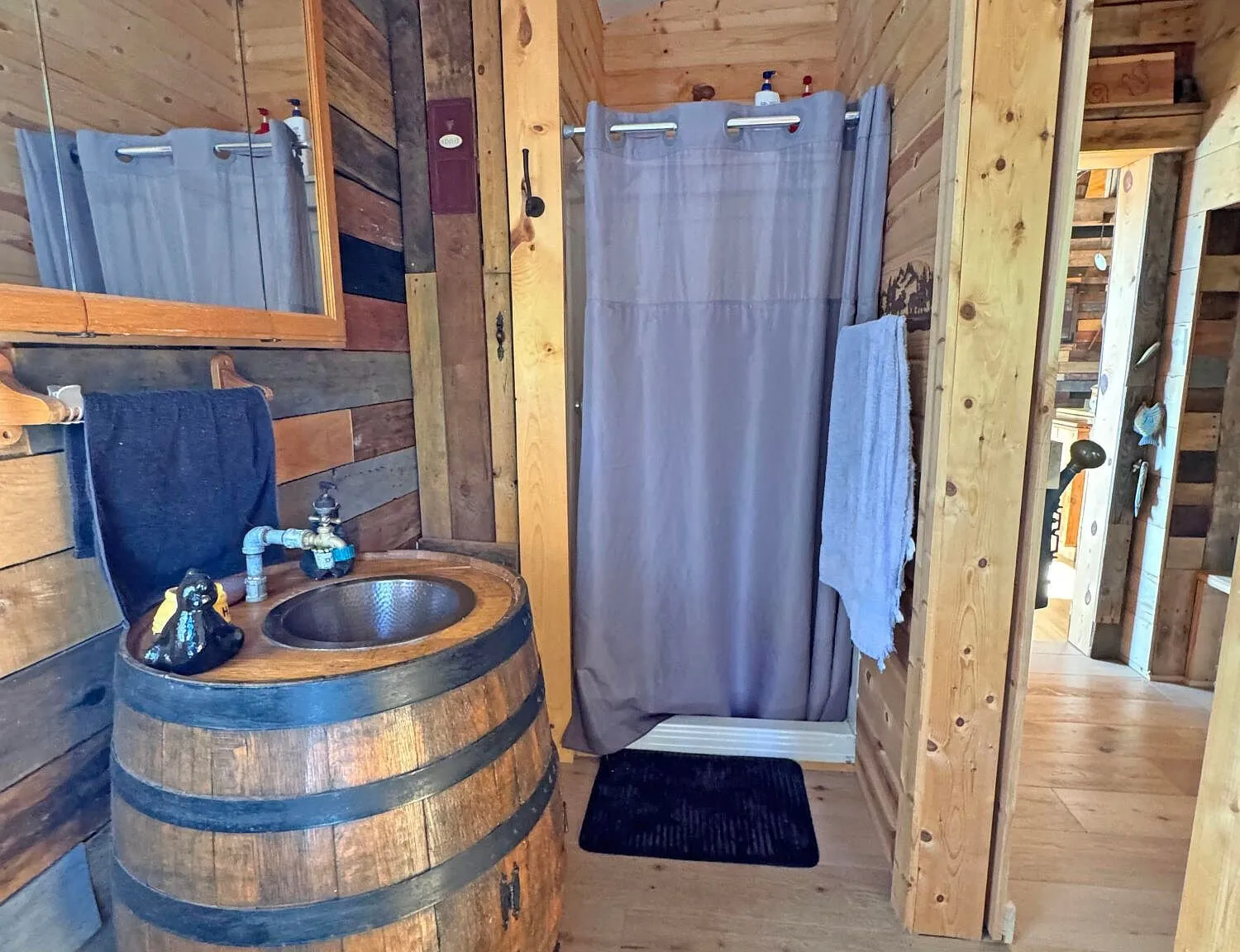 The bathroom's custom barrel sink against the plank wall