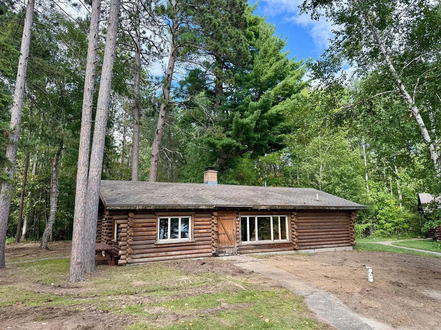 The second cabin from the lawn with the pines