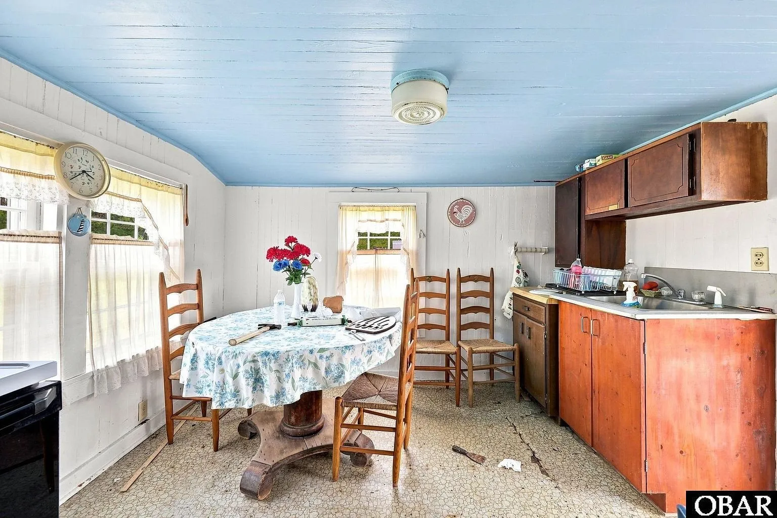 The dining area under a blue ceiling with a table and wood cabinets