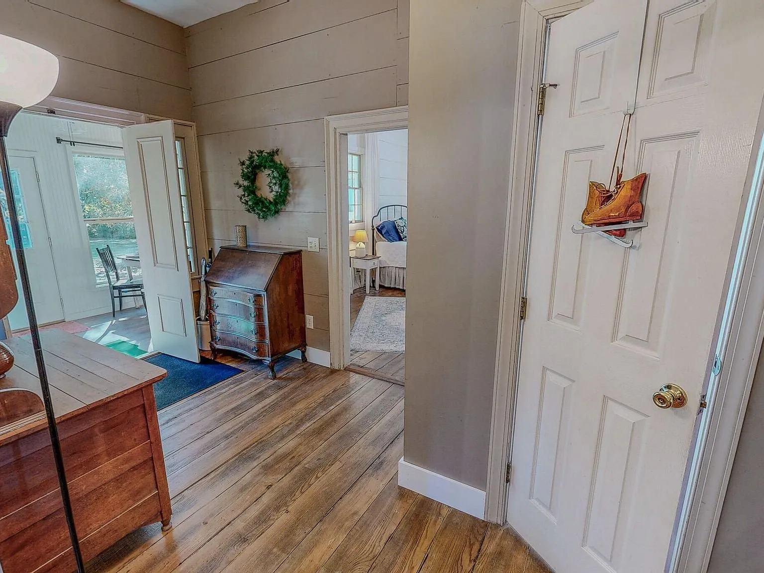 A hallway connecting two bedrooms, with a wreath on an interior door