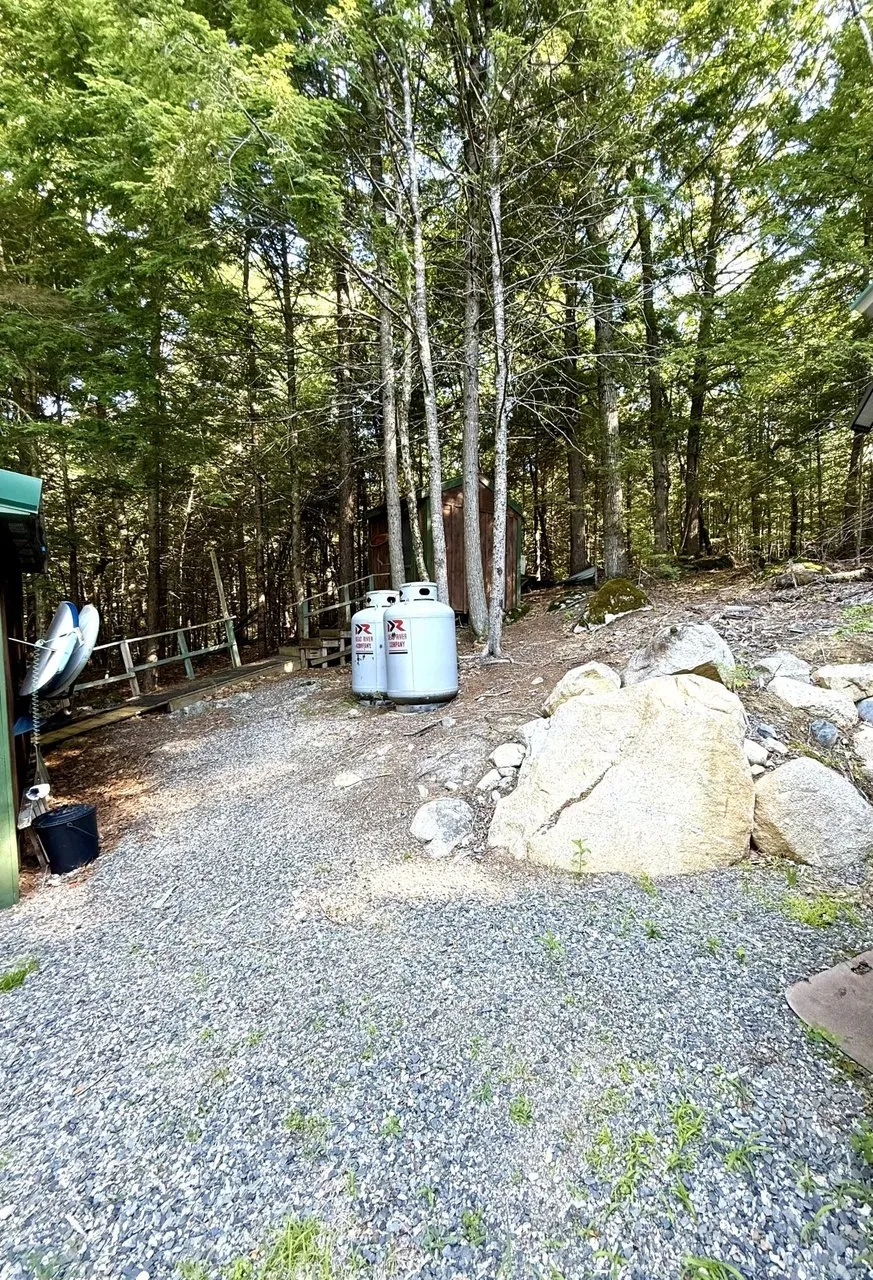 The gravel yard with two propane cylinders, the satellite dish and the boulders
