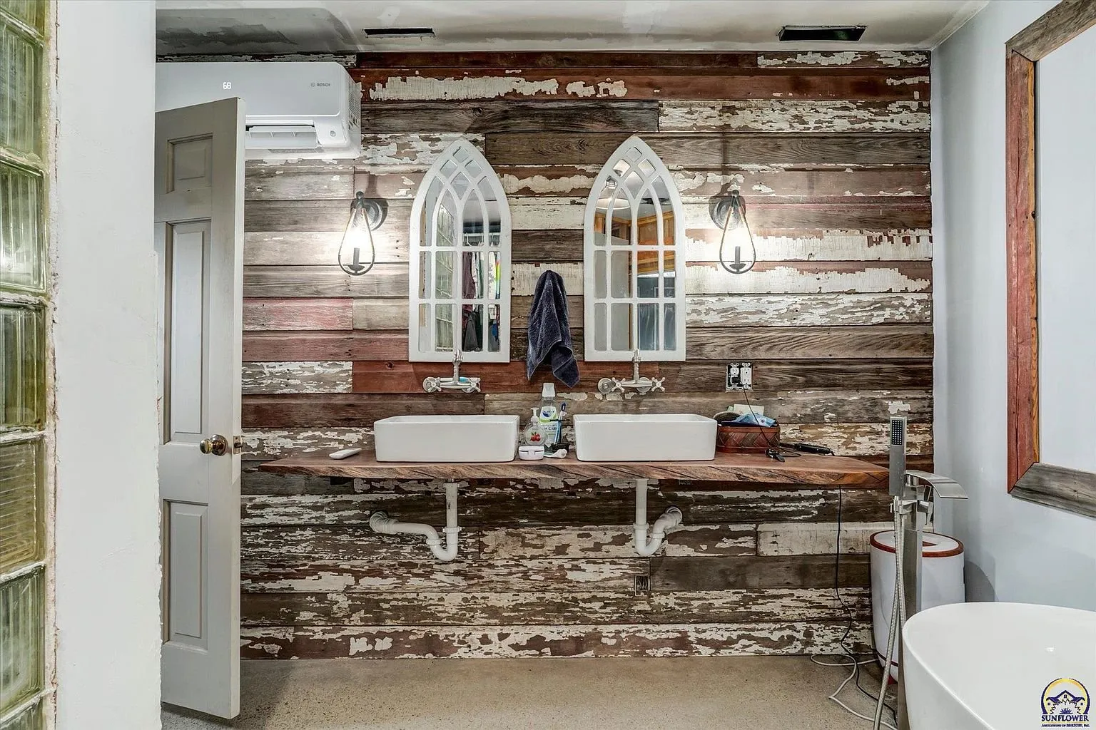 The double sinks on the reclaimed wood wall with the arched mirrors