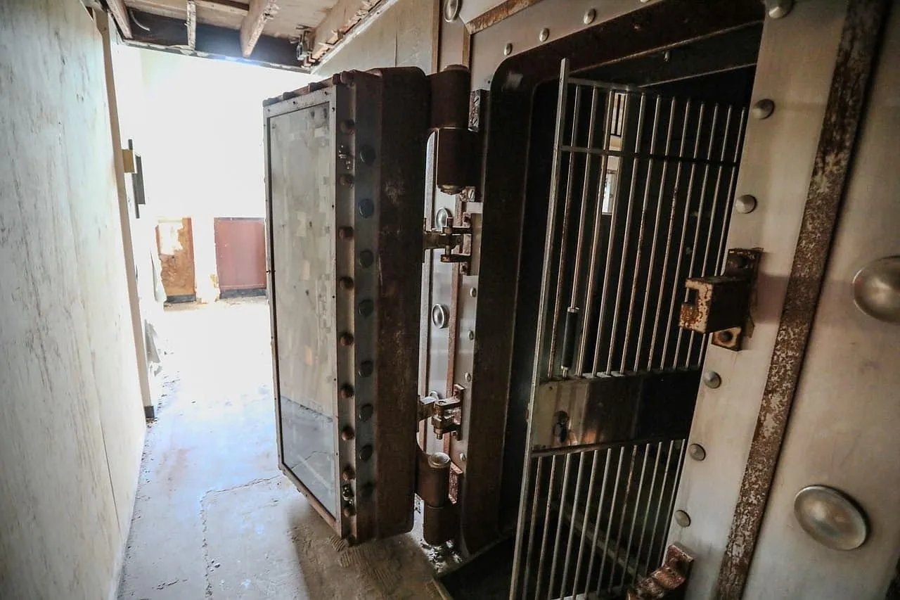The bank vault door standing open with the barred day gate inside it