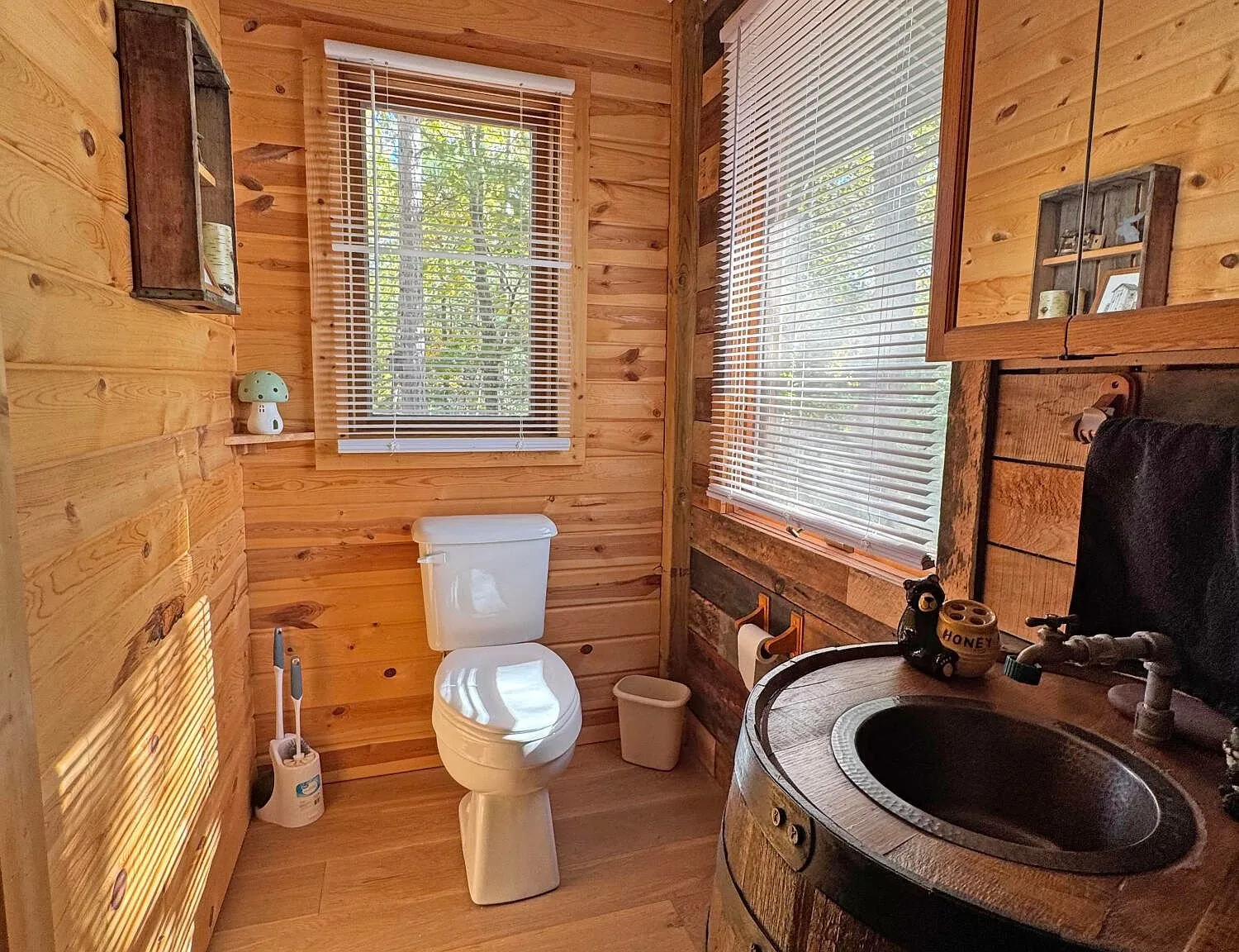 The bathroom with the barrel sink, toilet and window