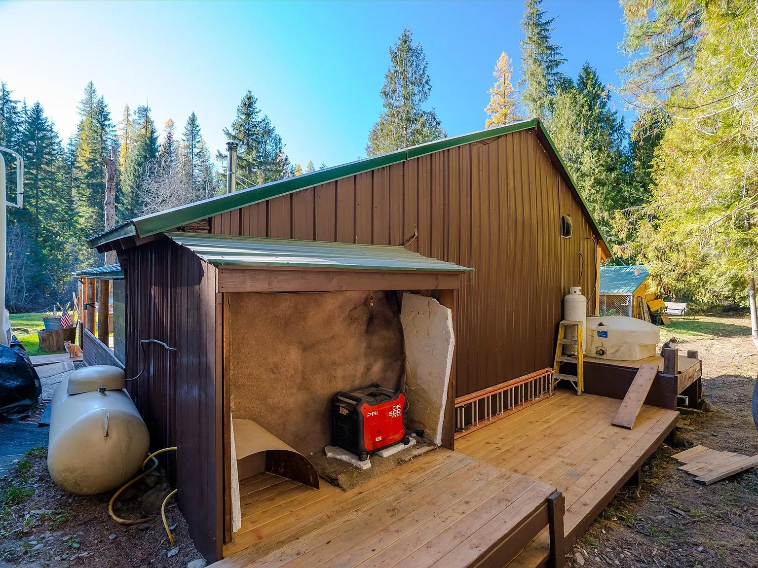 The cabin and clearing seen from above, bordered by the creek and surrounding timber
