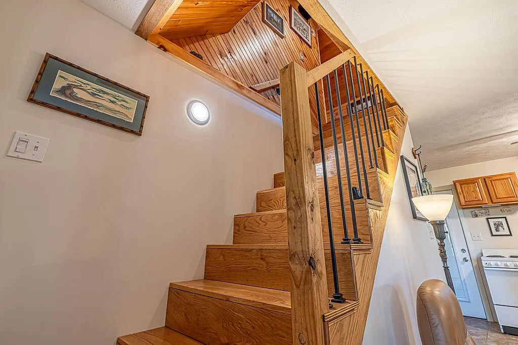 The second-floor loft bedroom beneath the sloped, tongue-and-groove pine ceiling