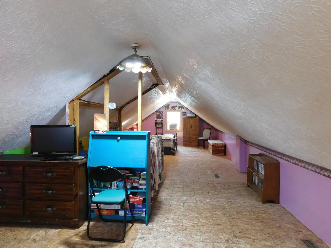 The loft with a television and shelving along the low wall