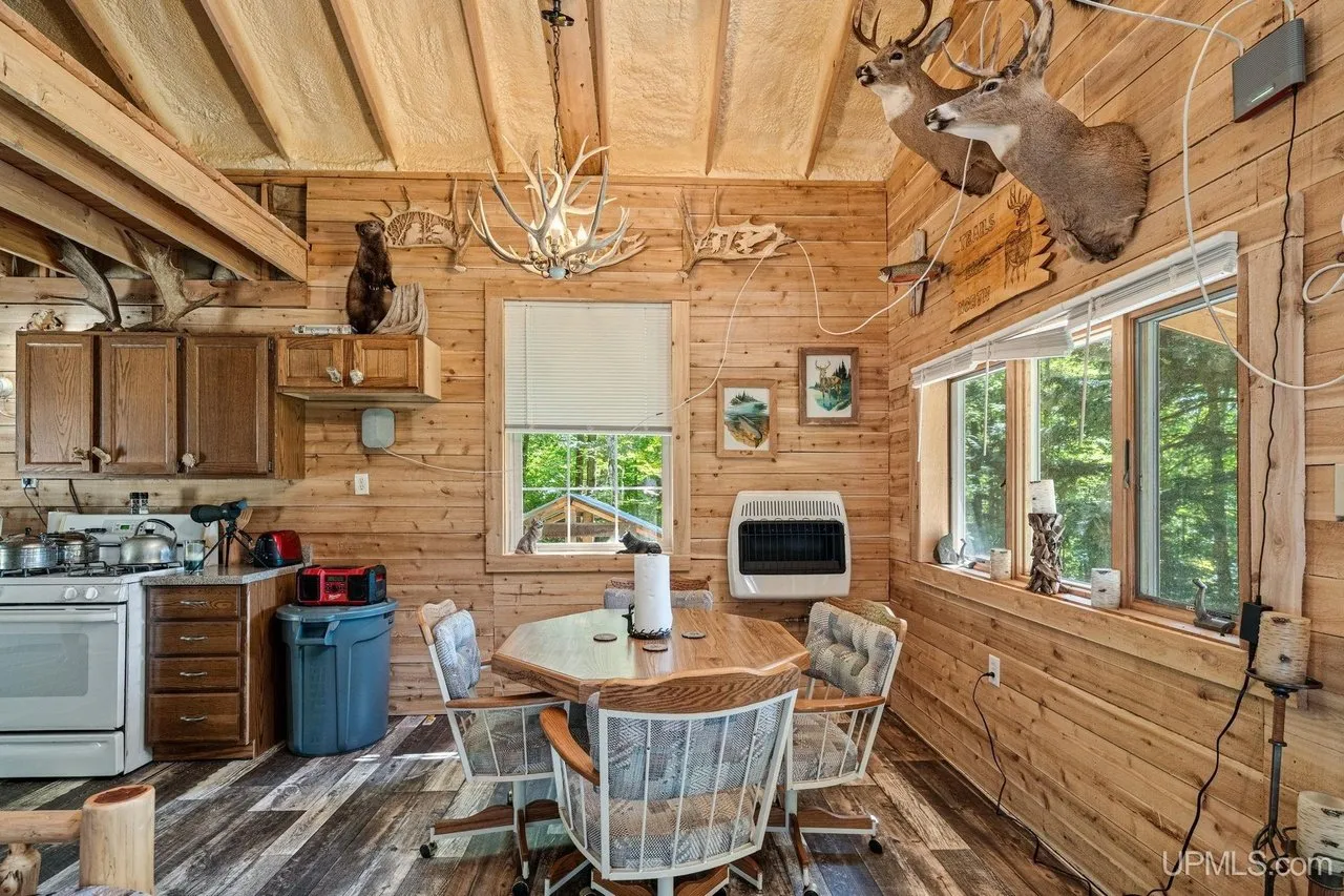 The dining table by the windows with the kitchen behind