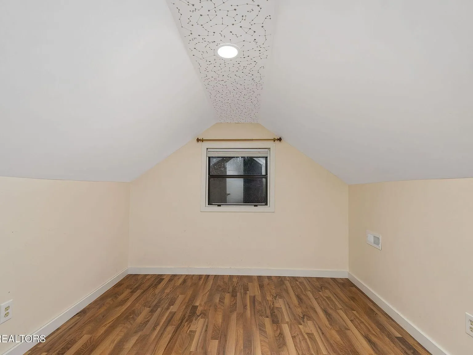 A second upstairs room with a dormer window and wood flooring