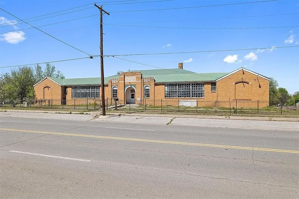 The school from the street with the utility pole and the fence