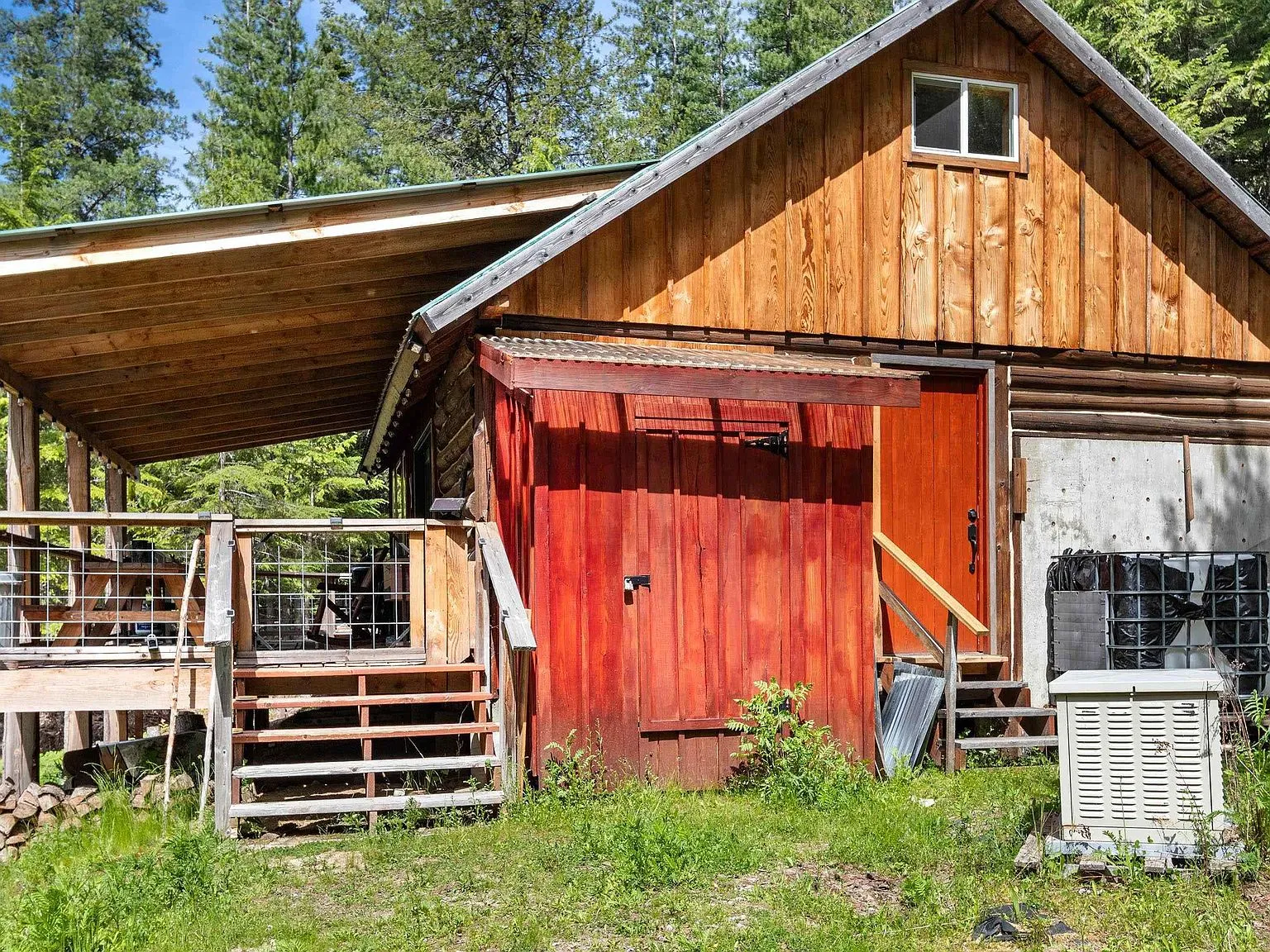 A backhoe and generator included with the property, parked in a grassy clearing