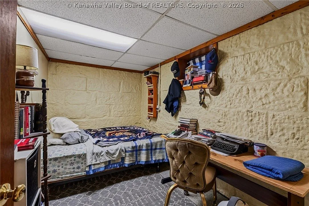 A basement bedroom with a twin bed, bookshelf and stone-finished walls