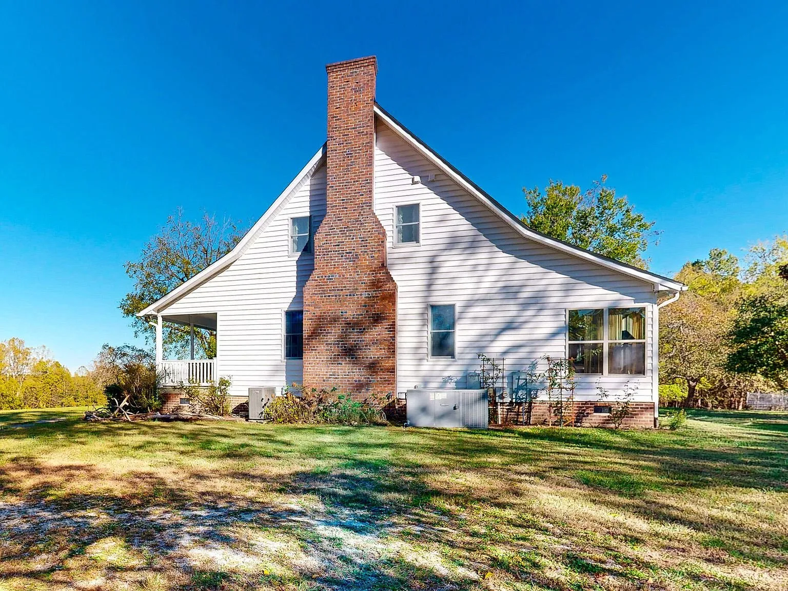 The farmhouse's brick chimney and gabled roofline against a blue sky