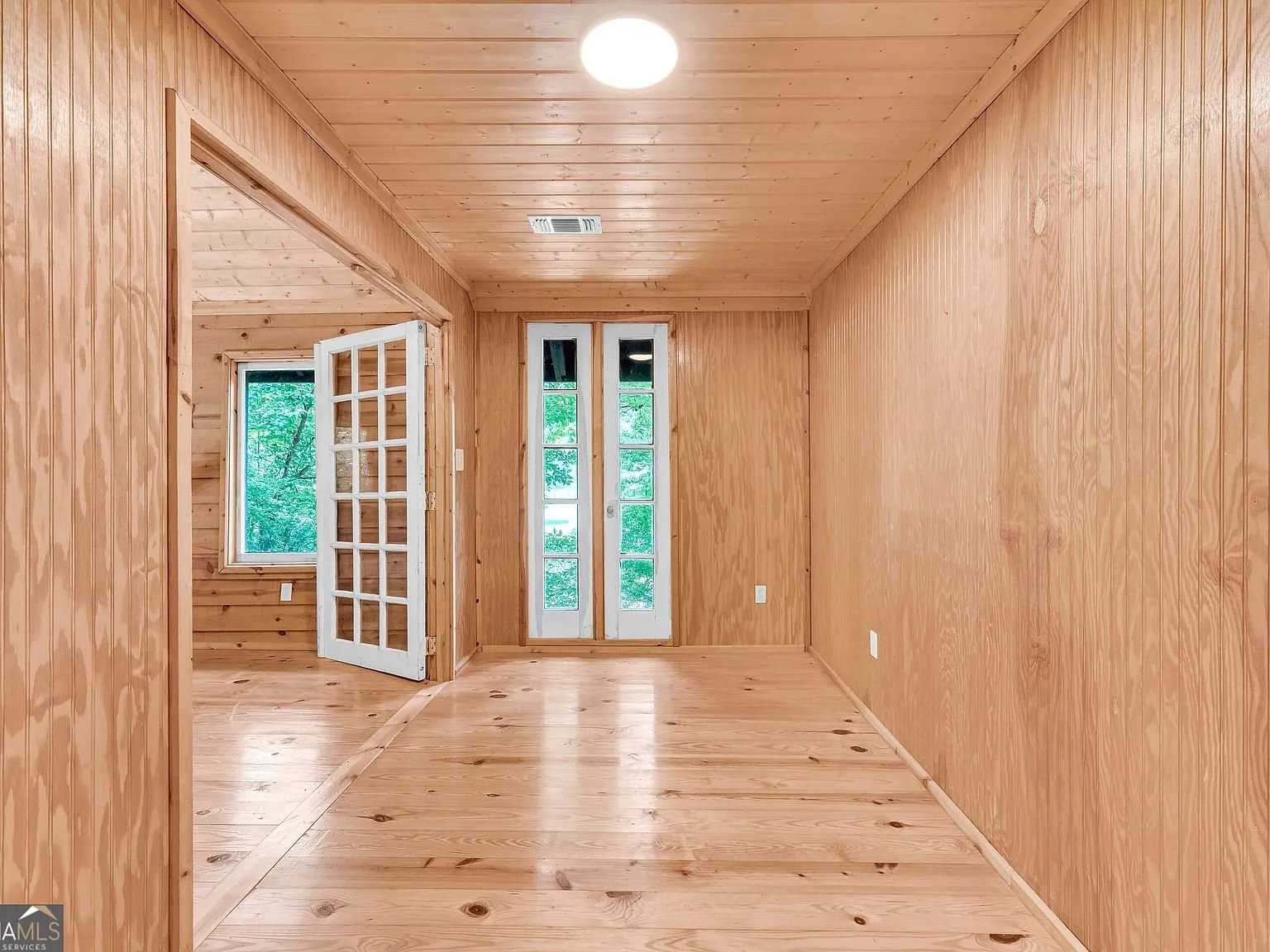An upstairs room with windows looking out over the wooded property
