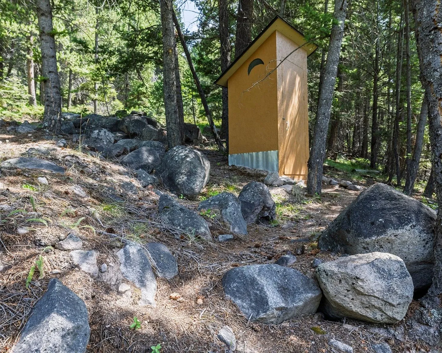 Inside the outhouse, a simple wood-paneled interior with a built-in seat