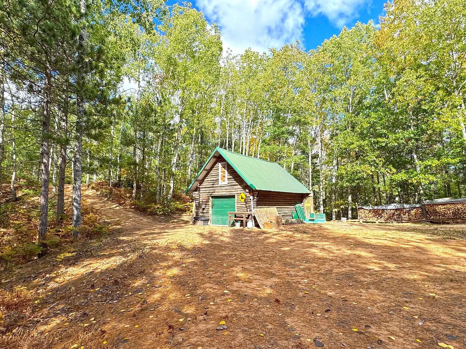The detached log garage with its green door, set back in the trees