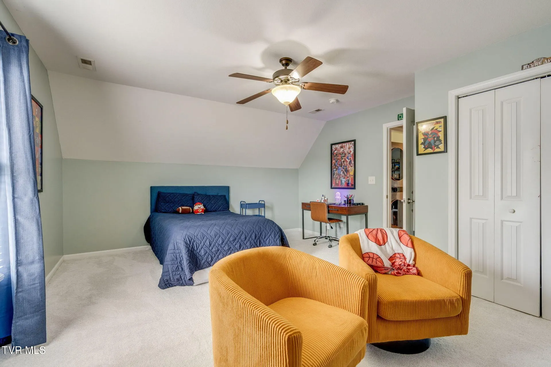 A bedroom with a bed, two armchairs and a closet with double doors