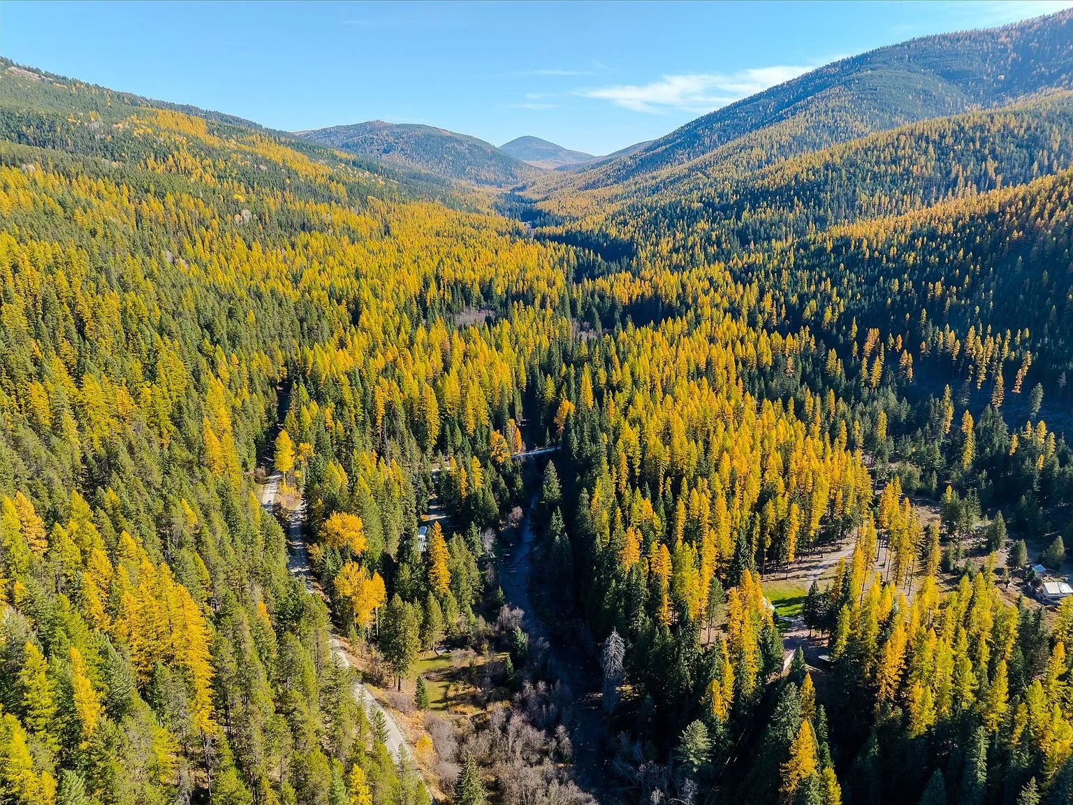 A wide aerial view of the cabin and RV parked beside the tree line