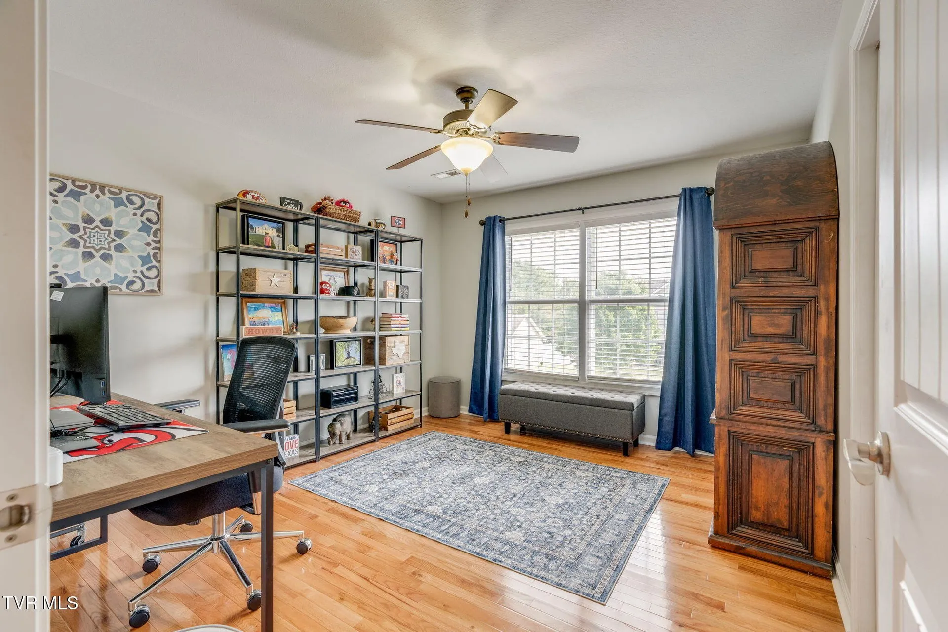 A room with bookshelves, a desk and a window seat