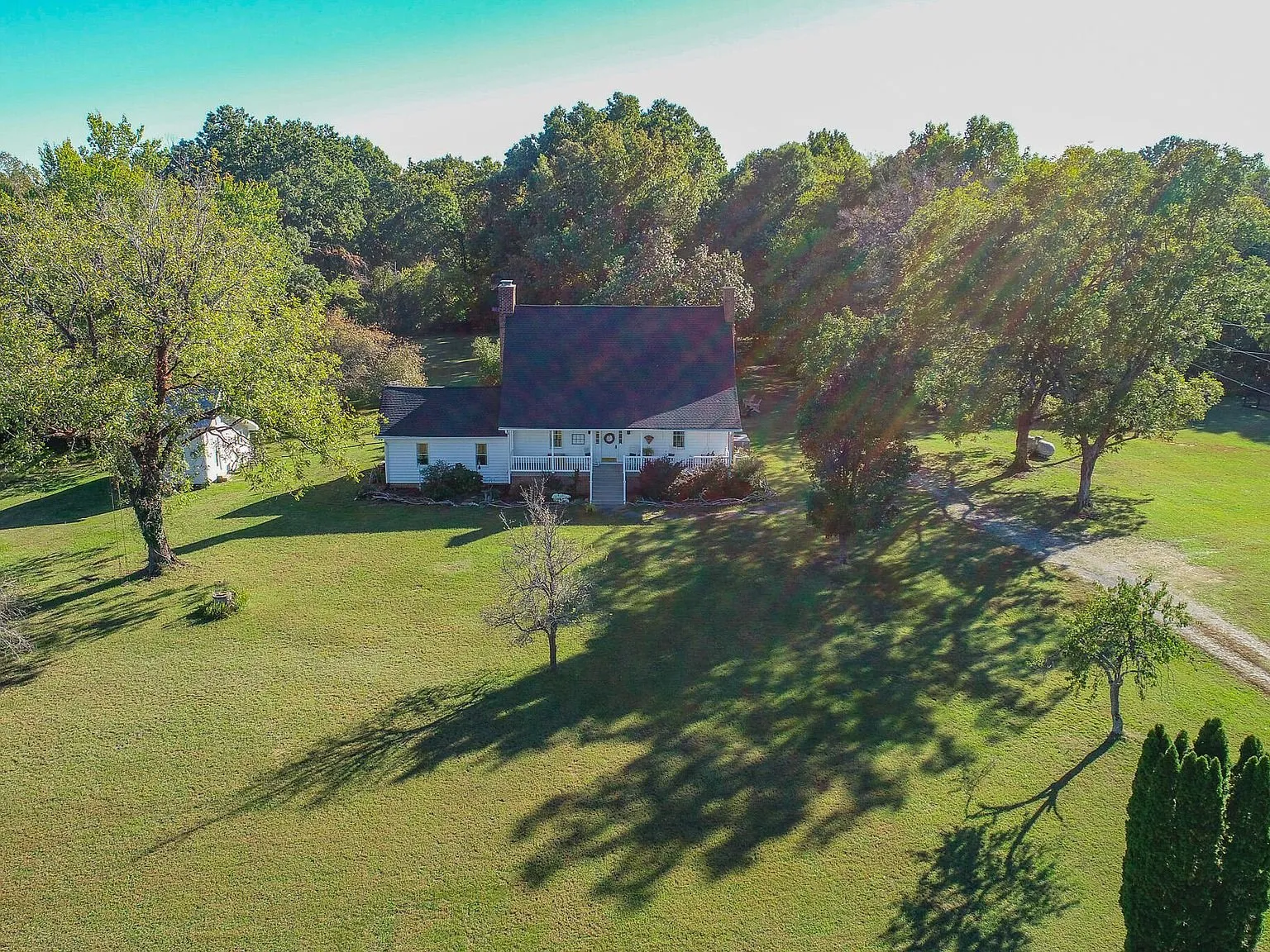 A wide aerial view of the property's open pasture and wooded edges