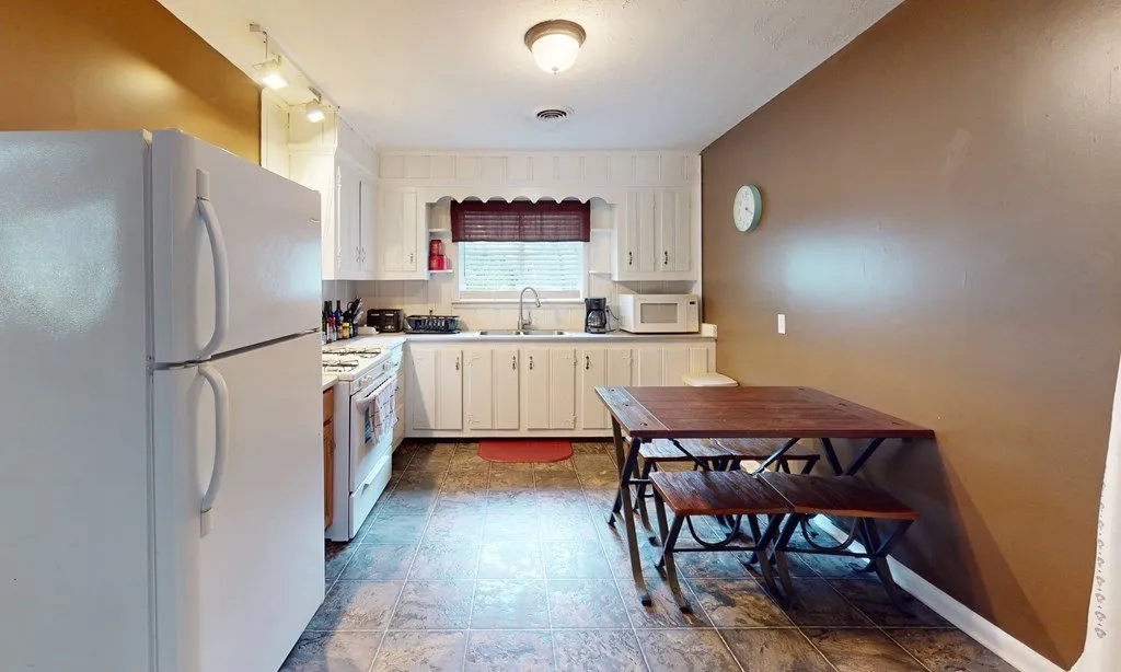 The second house's kitchen with white cabinets and a dining table