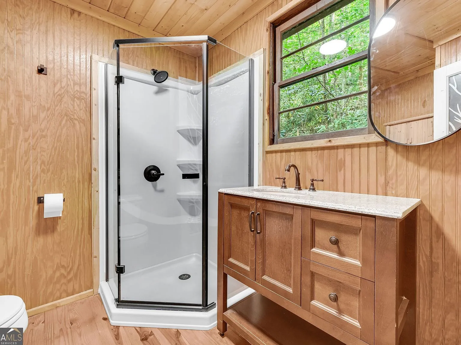 A bathroom vanity and toilet with a tree-patterned shower curtain