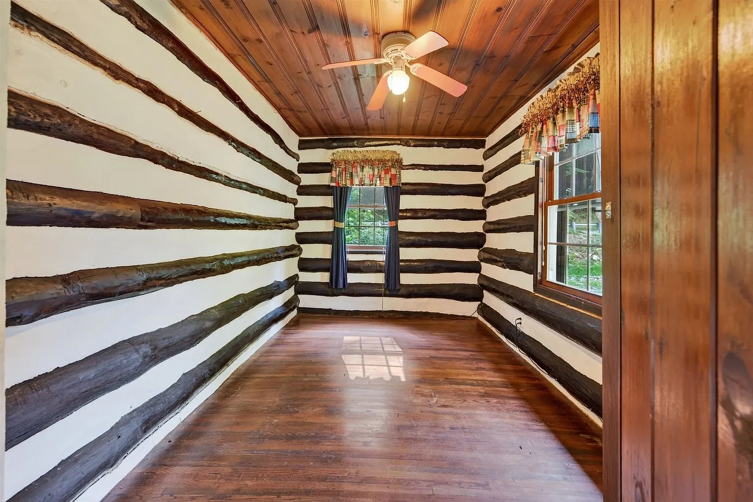 A bedroom with a window in the log wall