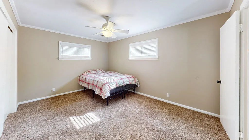 A bedroom in the second house with carpet and a window