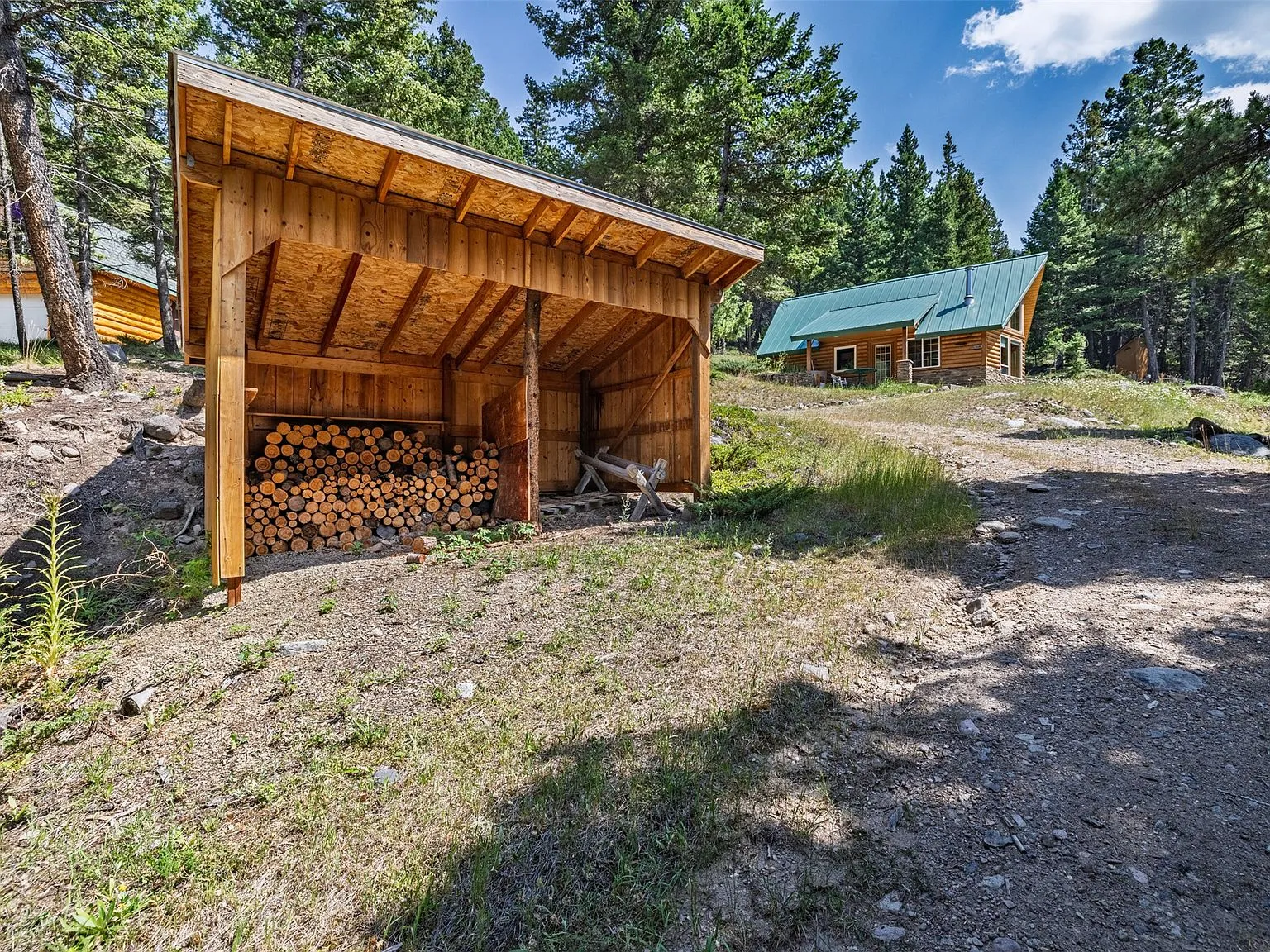 The woodshed stacked with firewood, with the main cabin visible downhill
