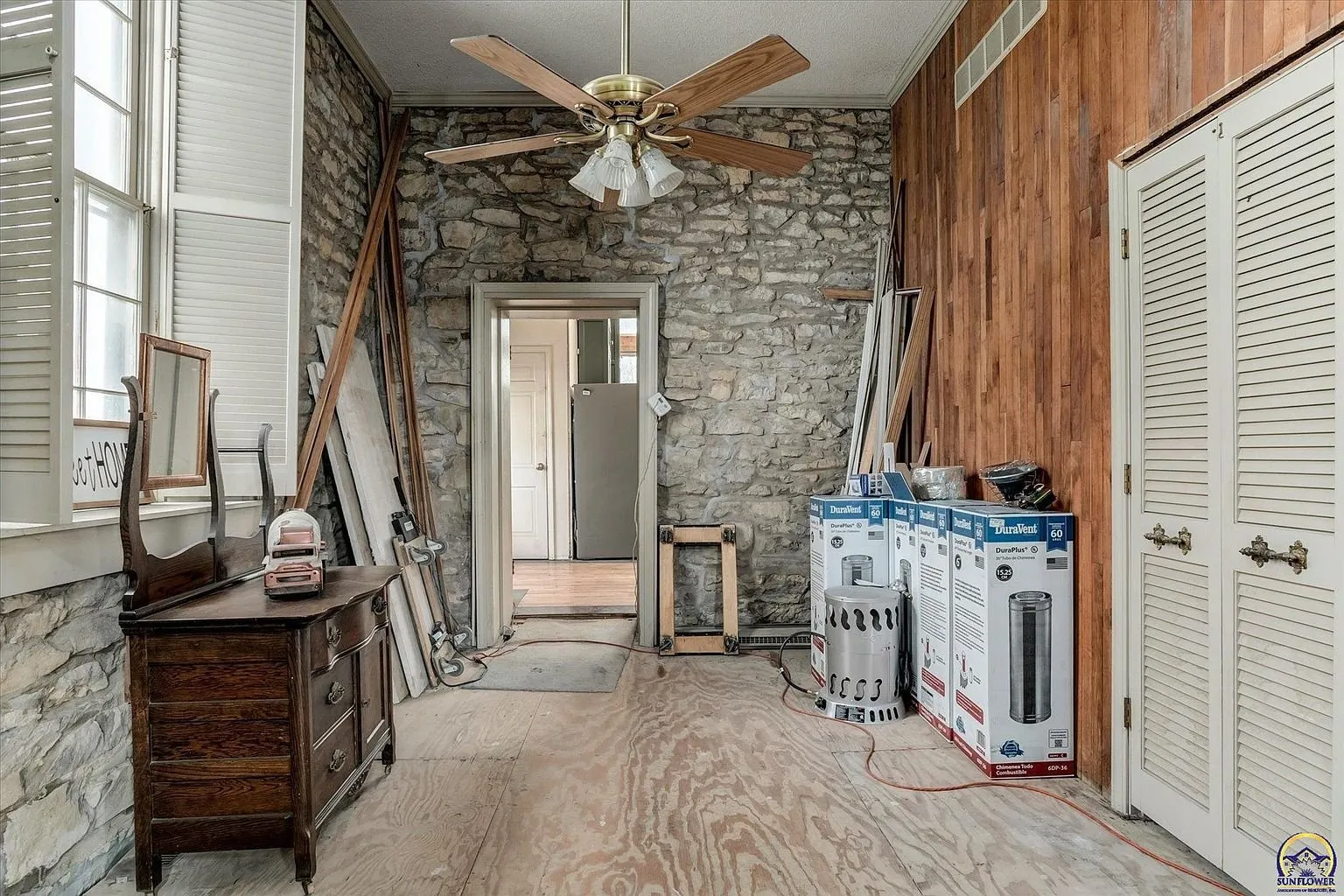 The hall with the stone wall, the ceiling fan and the closet doors