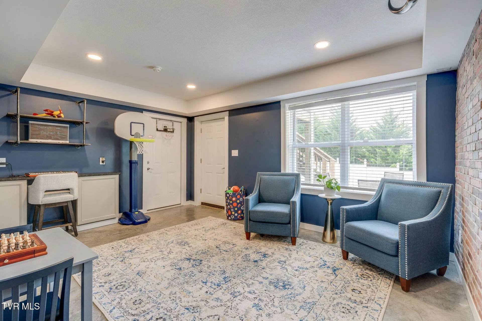 The finished basement room with armchairs, a rug and a window to the yard