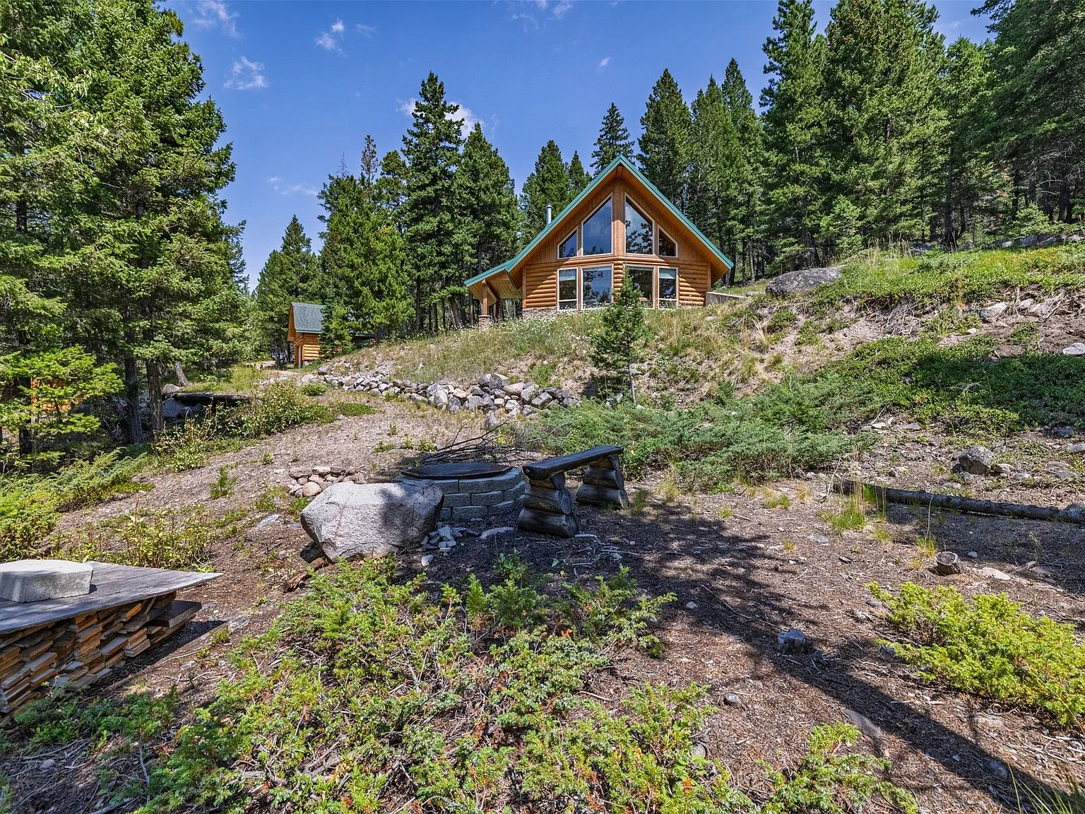 A wide gravel driveway winding past the woodshed toward the cabin