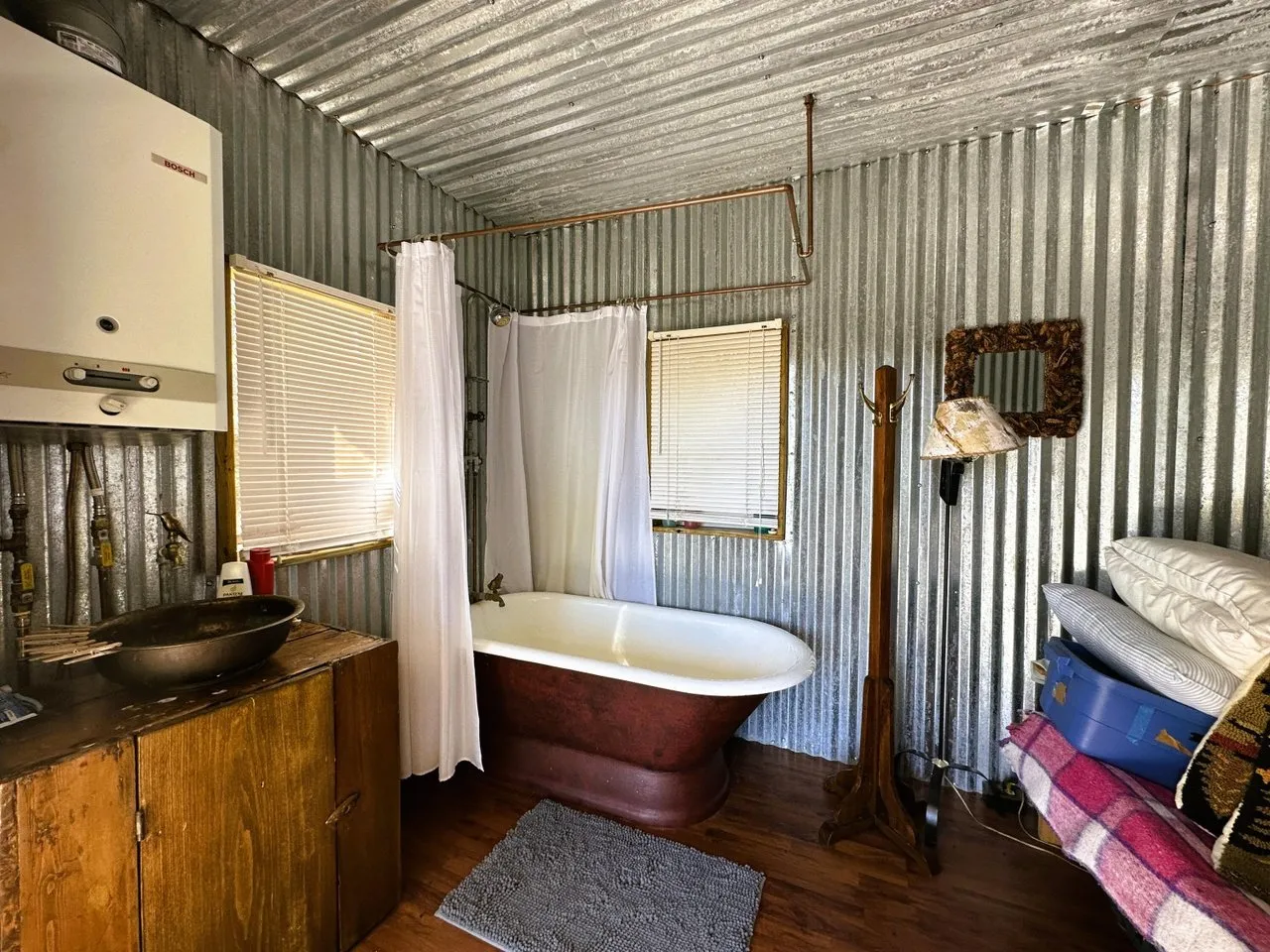Inside the bathhouse with the soaking tub, sink and corrugated metal walls