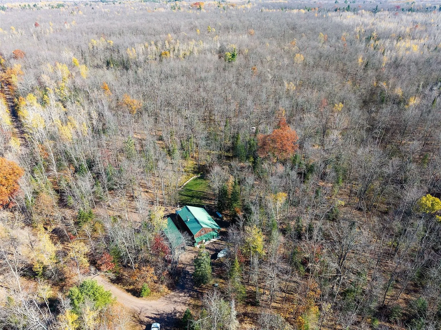 Aerial view of the home surrounded by wooded acreage