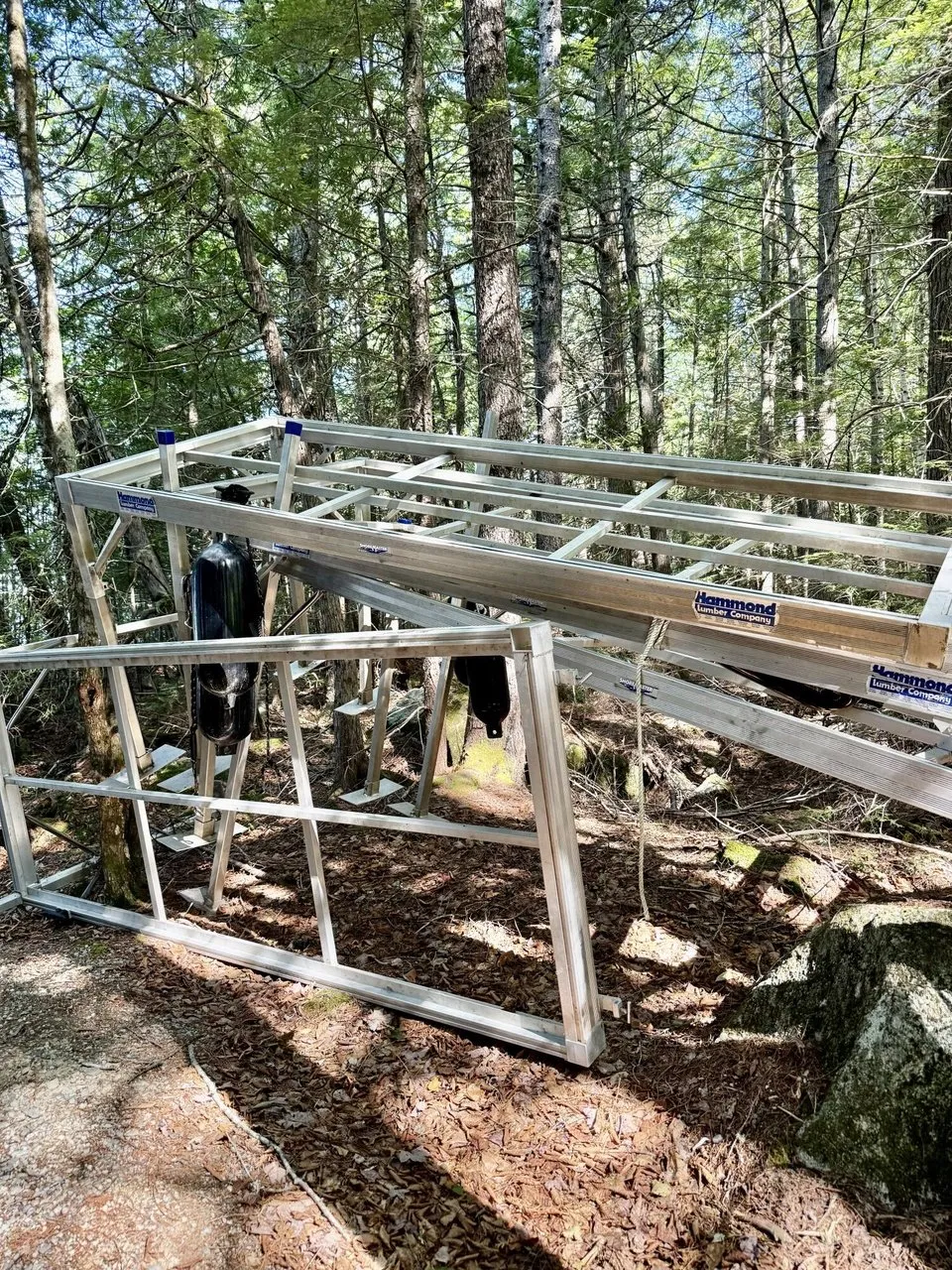 The sections of the aluminum dock stored in the woods