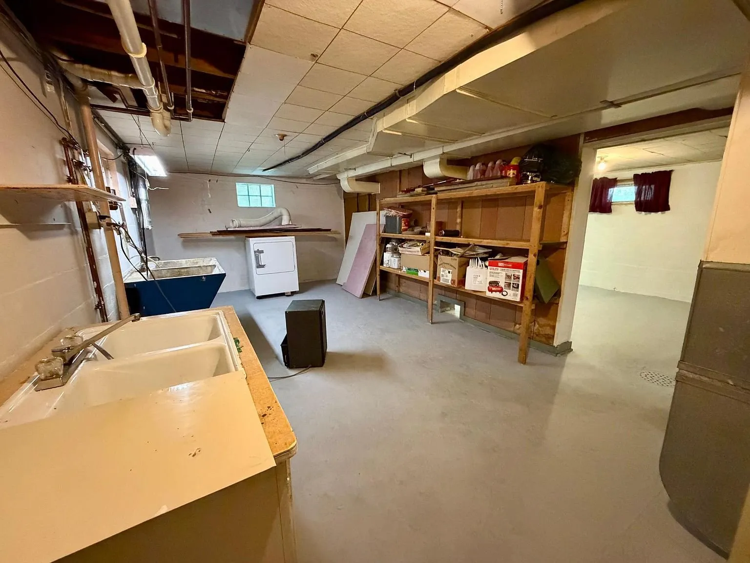 The basement with the laundry sink and the shelves