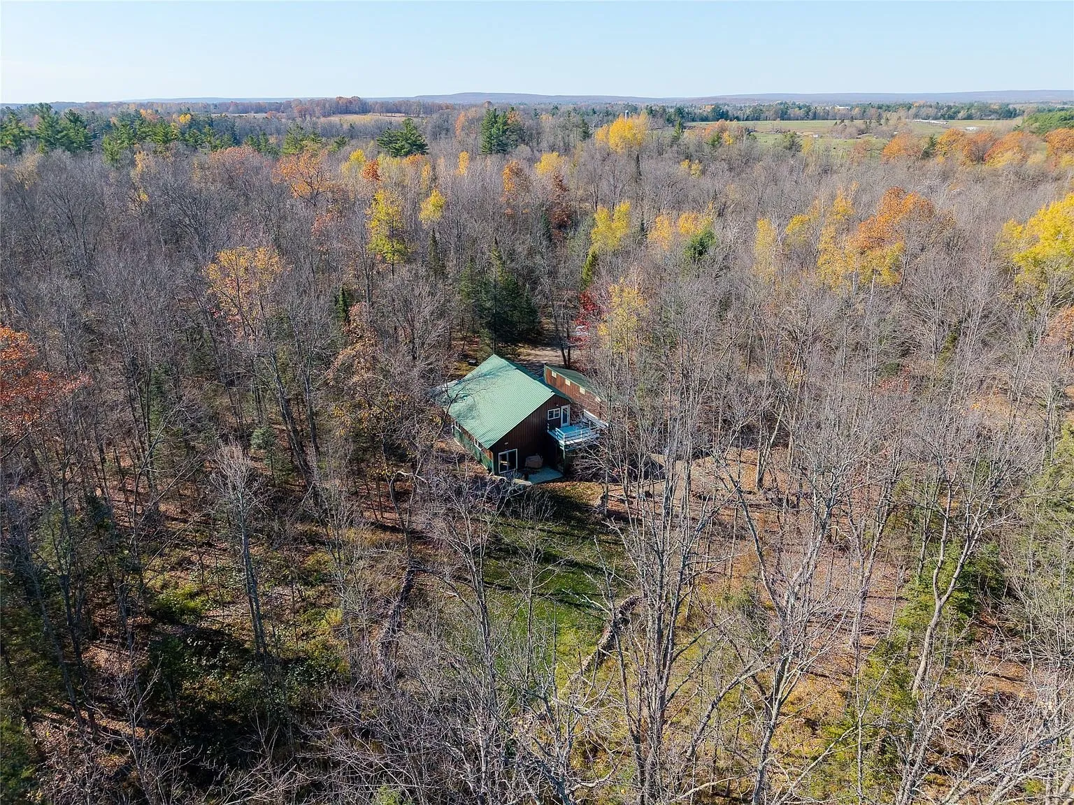 A wide aerial view of the surrounding farmland and wooded hills