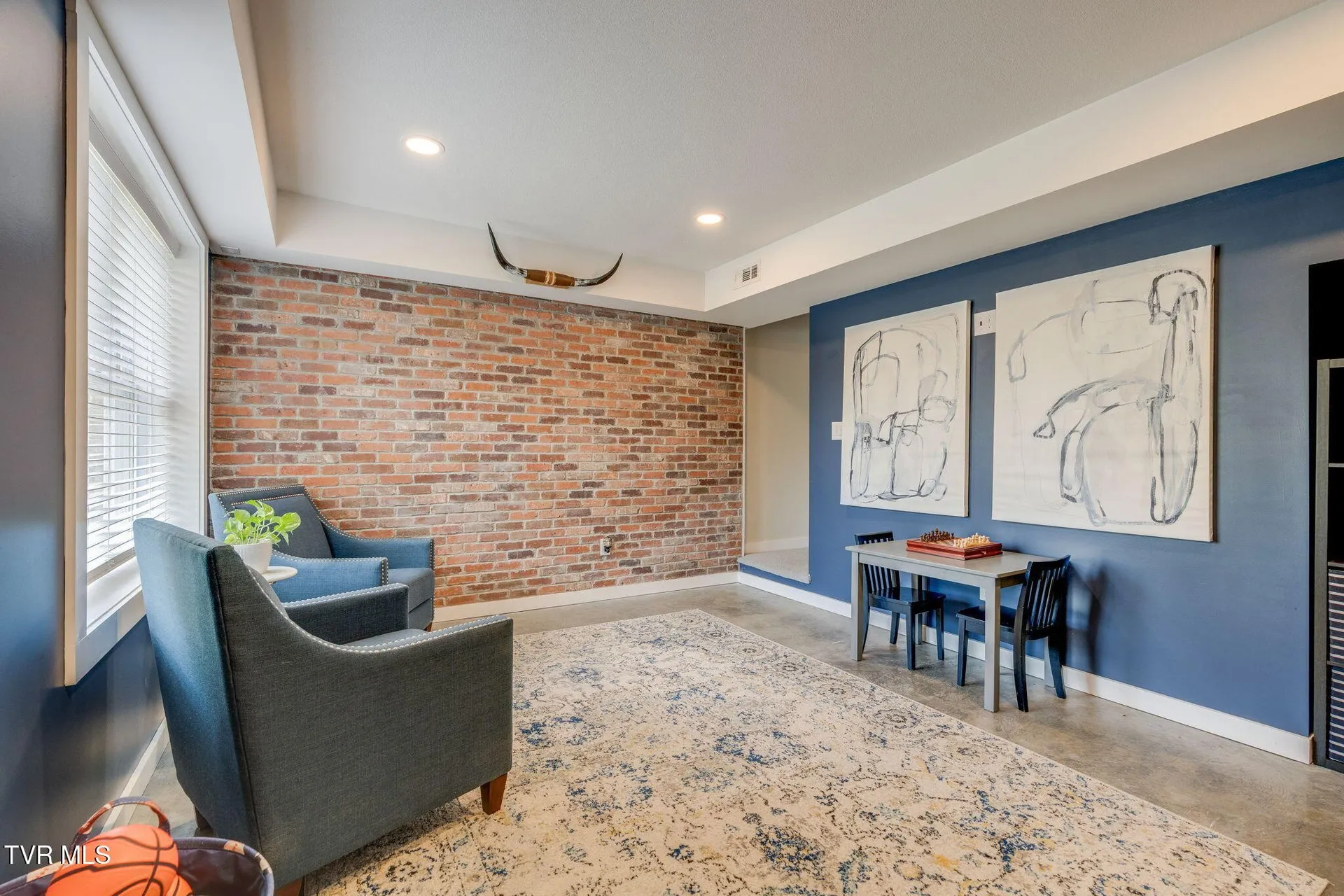The basement room with its exposed brick wall and a table and chairs